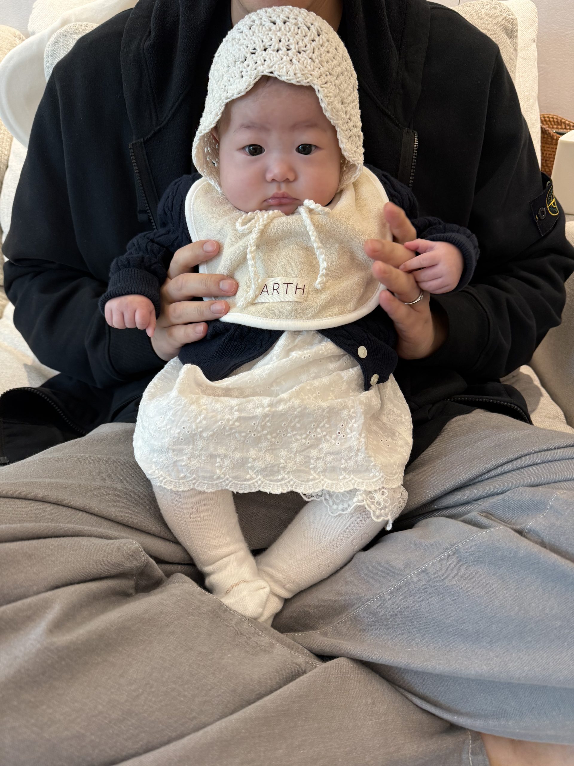 레이스 원피스와 보닛을 쓰고 아빠 무릎 위에 앉아 있는 아기